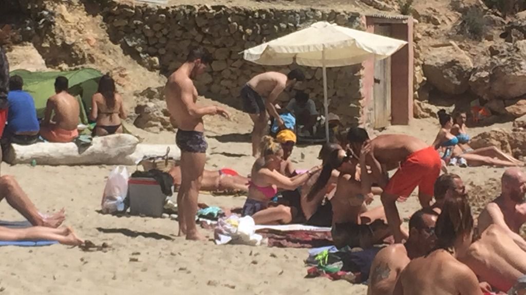 Bajo la sombrilla blanca, un hombre prepara mojitos en Cala Saladeta