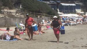 Dos vendedores ambulantes recorriendo la playa de Ses Salines