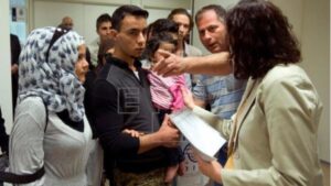 Un grupo de refugiados es atendido por un voluntario humanitario