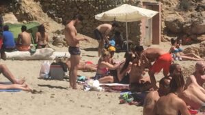 Bajo la sombrilla blanca, un hombre prepara mojitos en Cala Saladeta