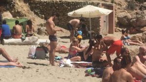 Bajo la sombrilla blanca, un hombre prepara mojitos en Cala Saladeta