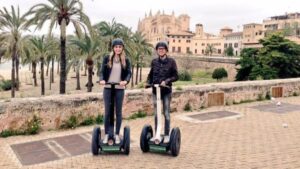 Dos turistas se fotograf&iacute;an en una de las rutas de los patinetes de moda en Palma