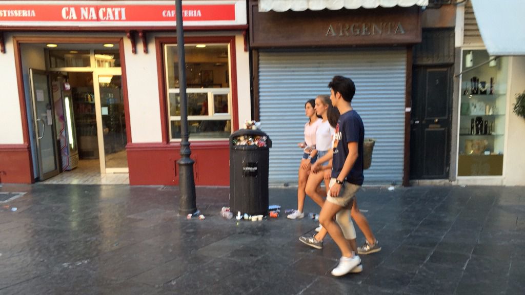 Jóvenes turistas sortean una papelera a rebosar