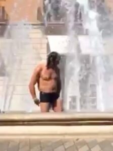 hombre ba&ntilde;&aacute;ndose en la fuente de la plaza de la reina
