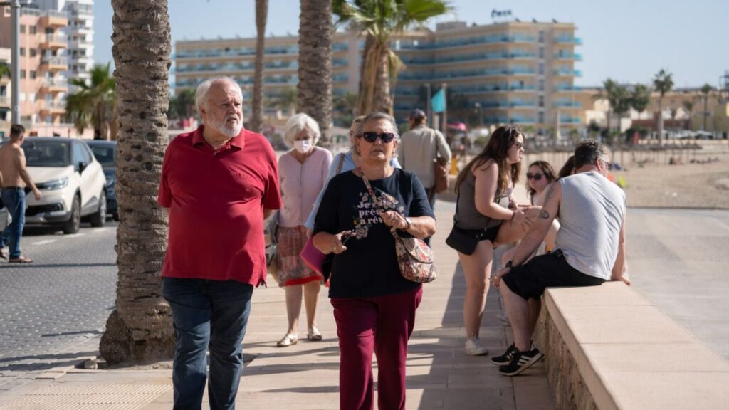 Turistas mayores pasean junto al mar en Cala Estancia.
