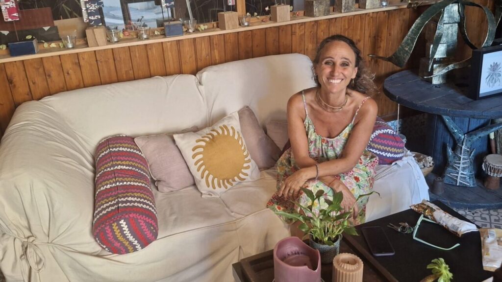 Esther Fuster sentada en un sofá en su estudio rodeada de arte.