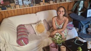 Esther Fuster sentada en un sofá en su estudio rodeada de arte.