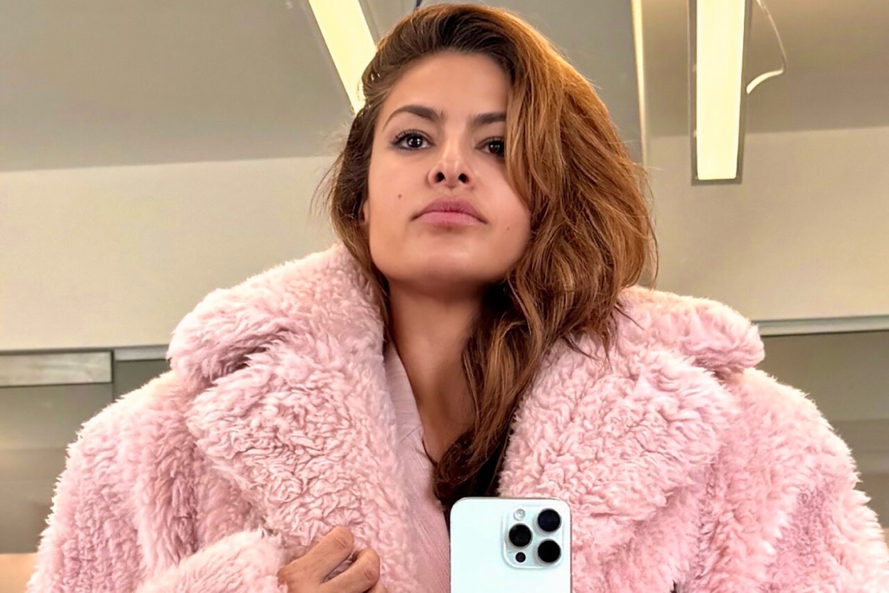 Eva Mendes con abrigo rosa en un entorno moderno