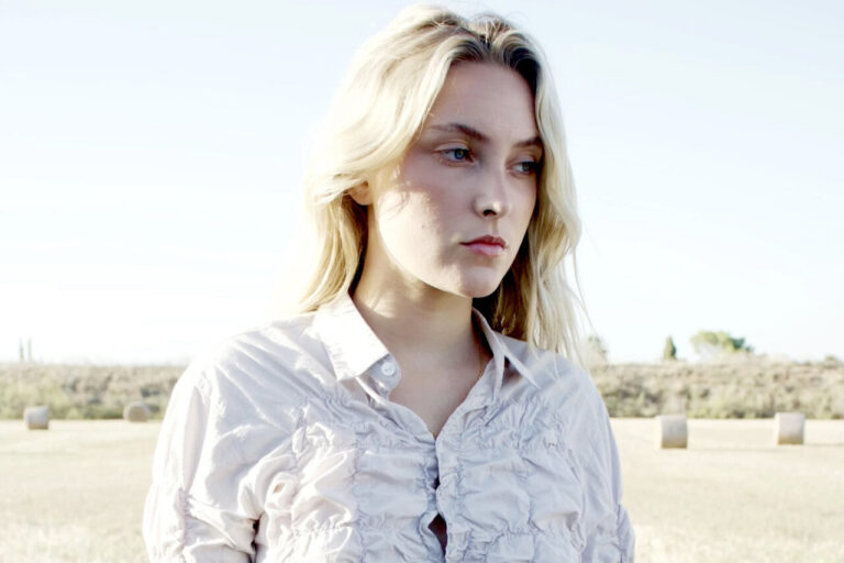 Maria Hein en un paisaje natural con luz suave y mirada reflexiva.