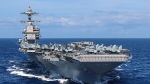 Vista de un portaaviones en el océano con aviones en la cubierta.