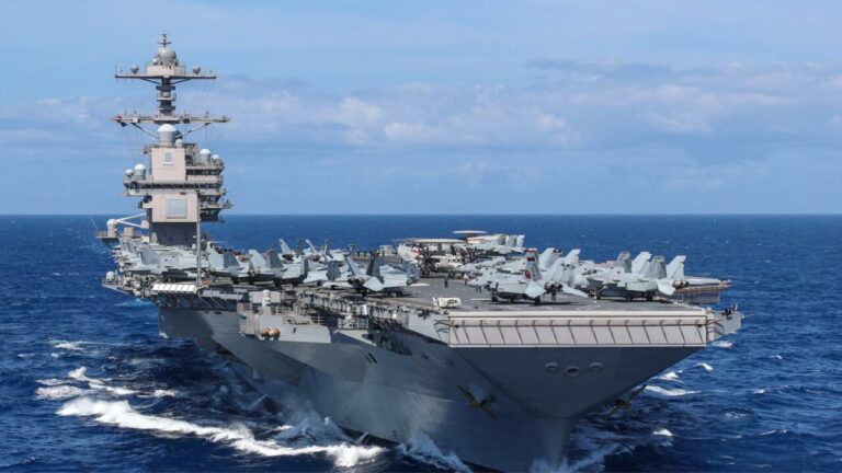 Vista de un portaaviones en el océano con aviones en la cubierta.
