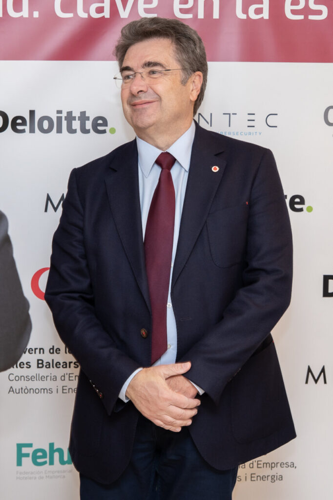 Hombre de pie en un evento de ciberseguridad con fondo de patrocinadores.