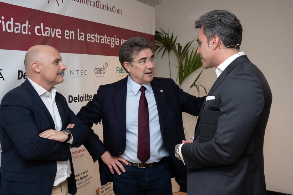 Tres hombres conversando en un evento sobre ciberseguridad.