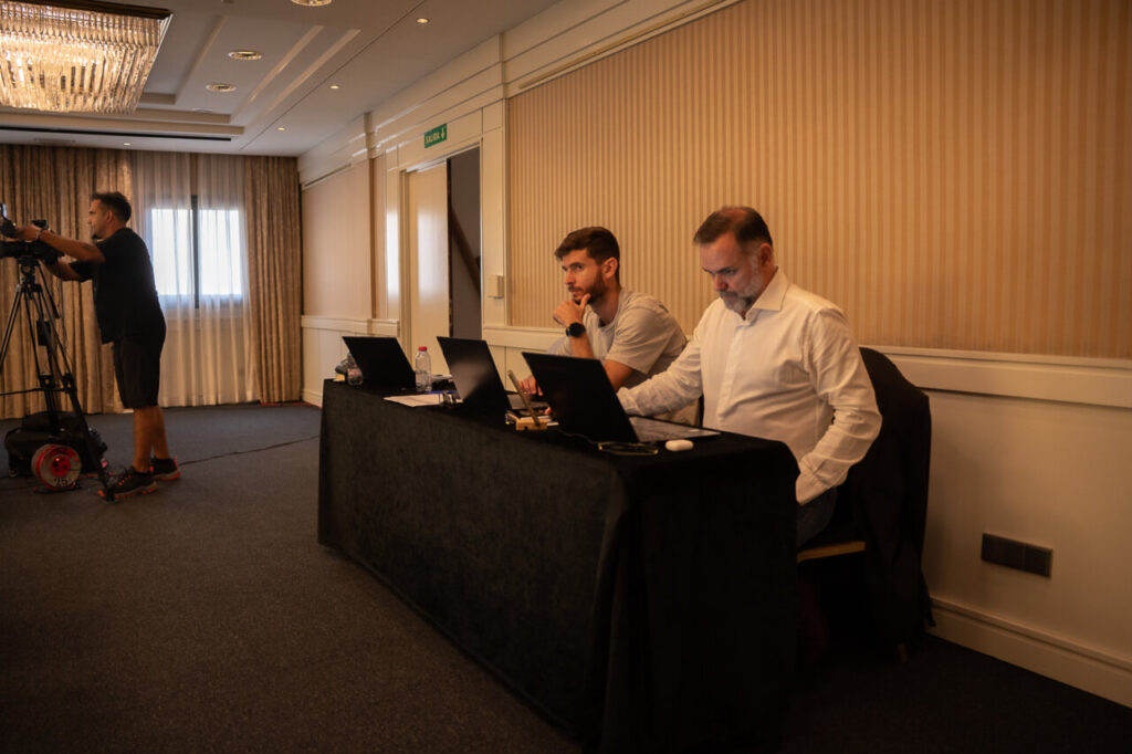 Dos hombres trabajando en laptops en un evento de ciberseguridad