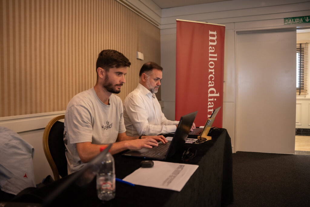 Dos hombres trabajando en laptops en un evento de ciberseguridad