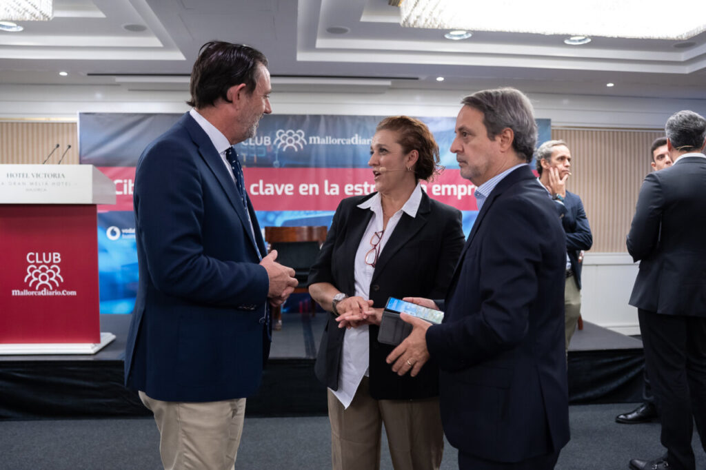 Tres personas conversando en un evento de ciberseguridad.