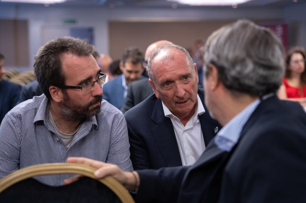 Tres hombres conversando en un evento de ciberseguridad.