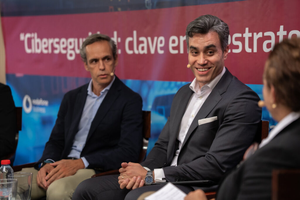 Panel de discusión sobre ciberseguridad con dos hombres sonriendo.