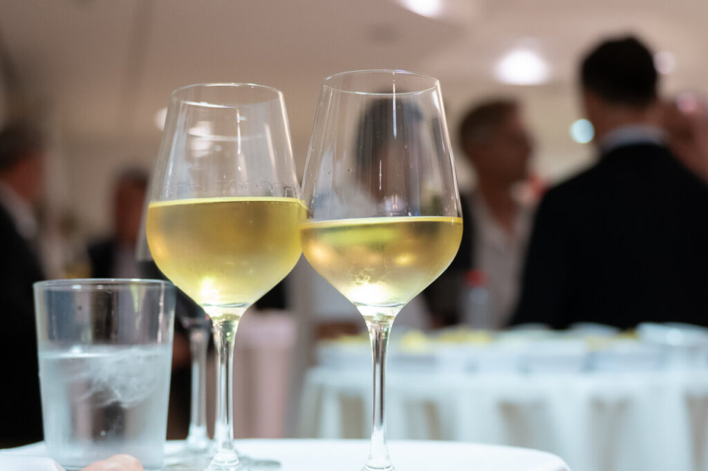 Dos copas de vino blanco en una mesa durante un evento social.