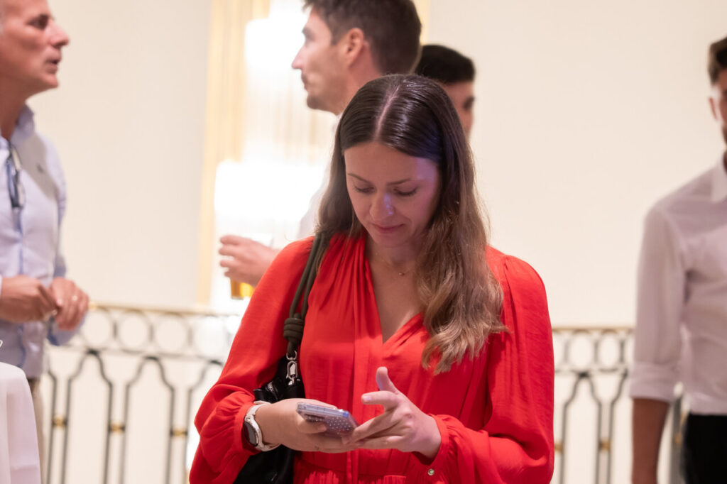 Mujer con blusa roja usando su teléfono en un evento social