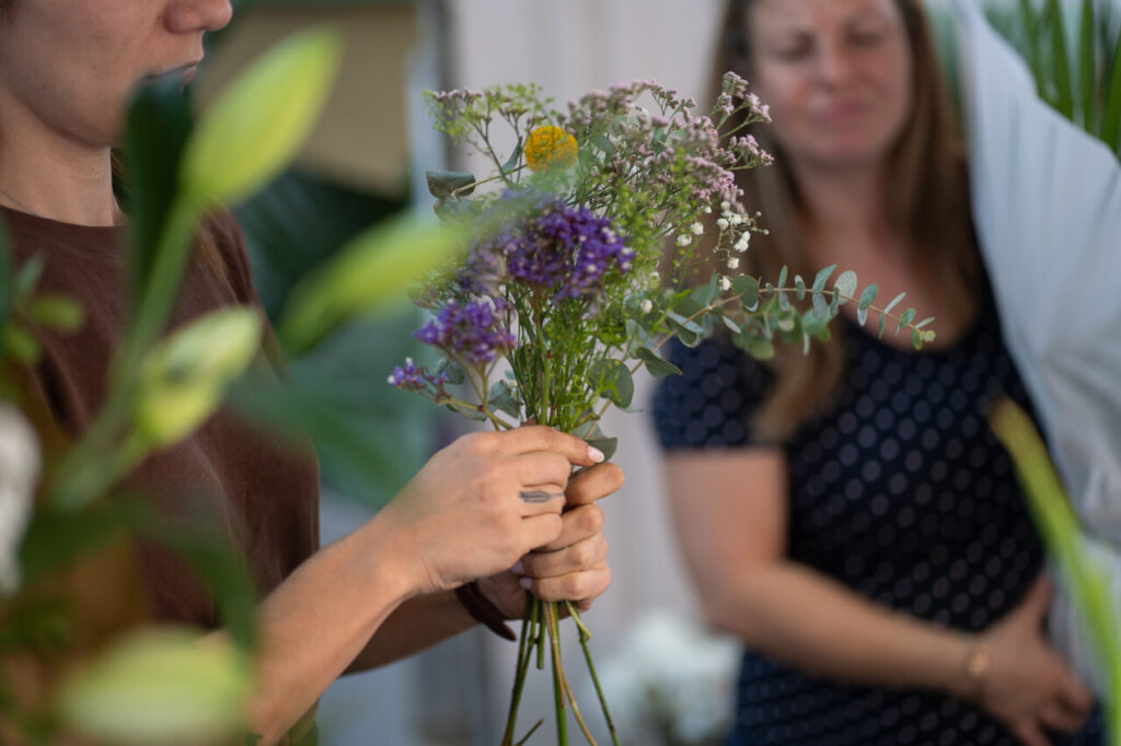 Mujer sosteniendo un ramo de flores variadas en un entorno festivo.