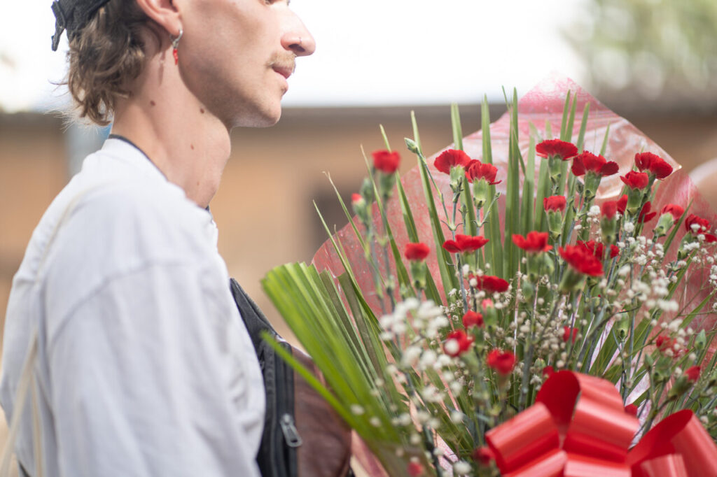 Hombre sosteniendo un ramo de flores rojas y verdes