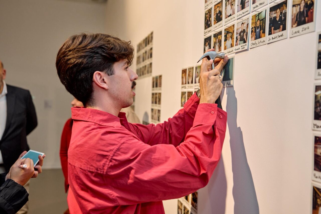 Persona colocando fotografías en una pared en la exposición de Porto Pi