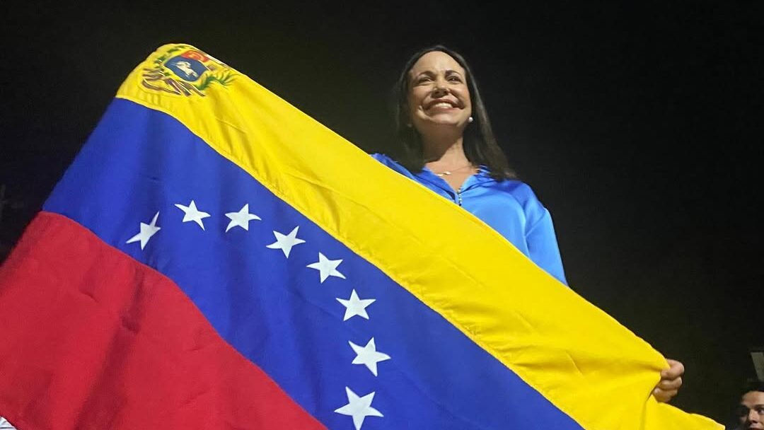 Mar&iacute;a Corina Machado sosteniendo la bandera de Venezuela con una sonrisa
