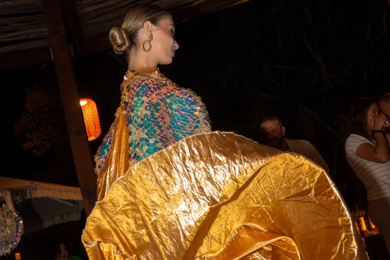 Mujer bailando con un vestido dorado en la celebraci&oacute;n del aniversario del hotel