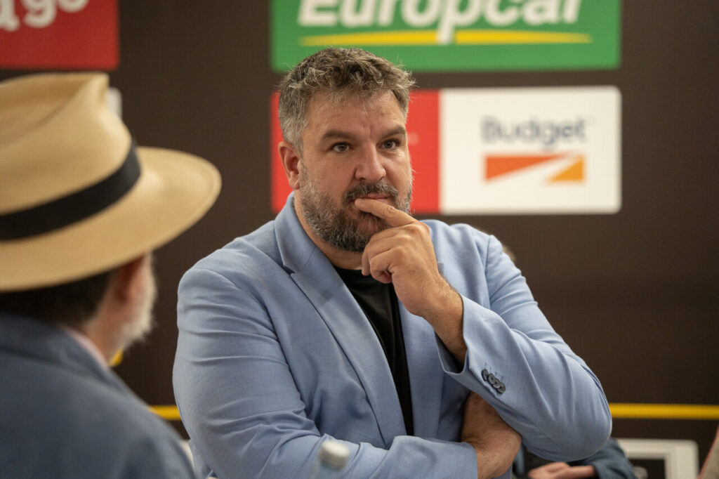 Reyes Rigo pensativo en un evento con otros asistentes