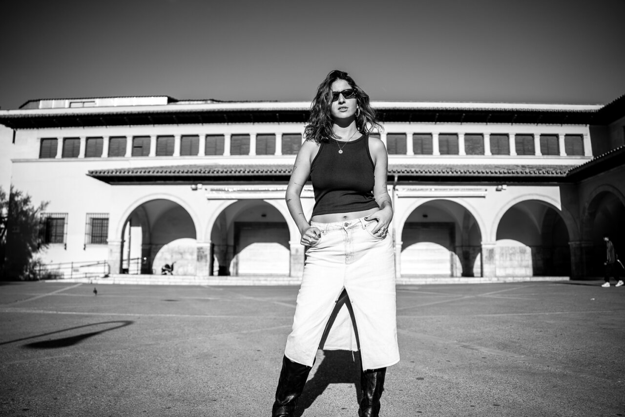 Mujer de pie en un lugar urbano con estilo moderno y gafas de sol.