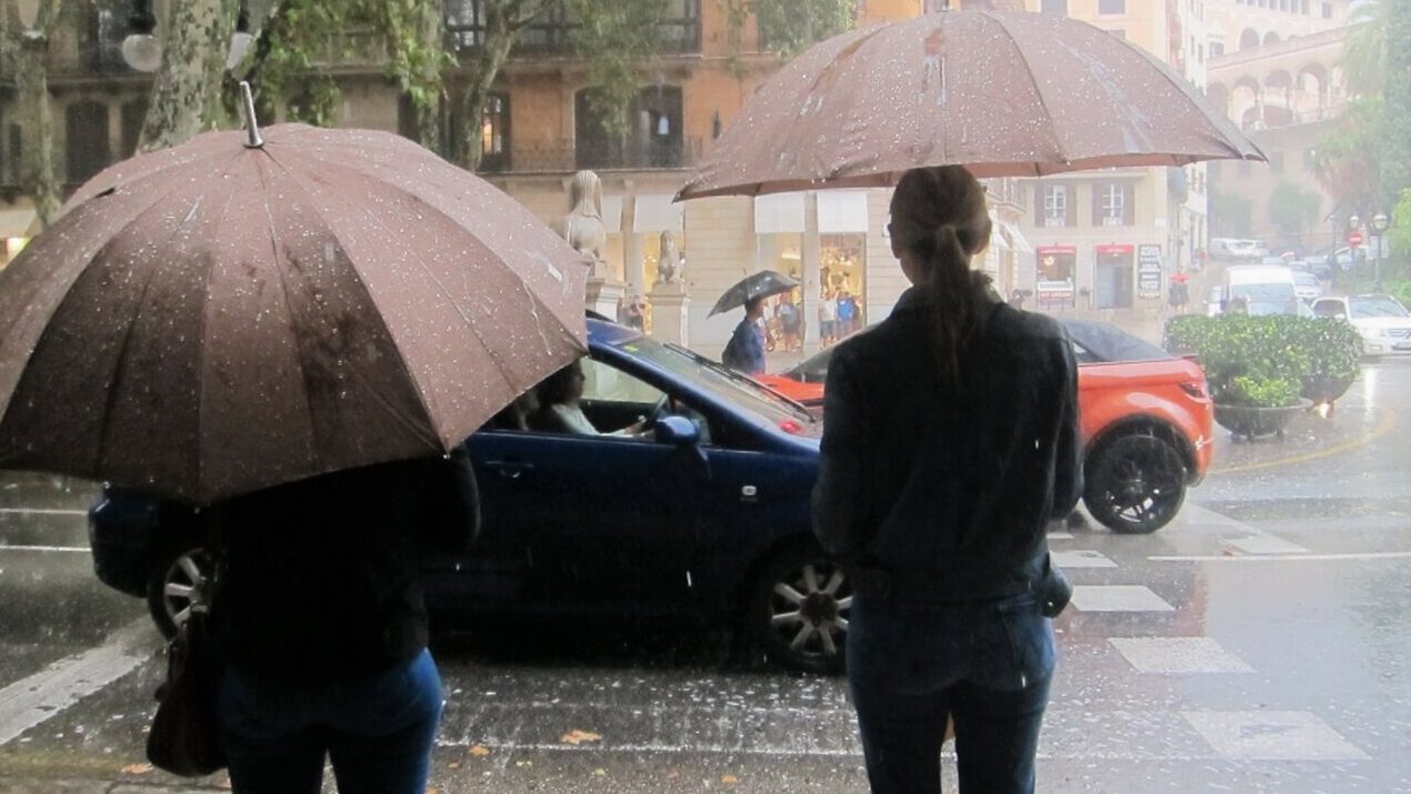 Personas con paraguas bajo la lluvia en una calle de Baleares