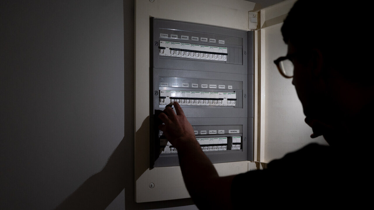 Persona ajustando un interruptor en un cuadro el&eacute;ctrico durante un apag&oacute;n