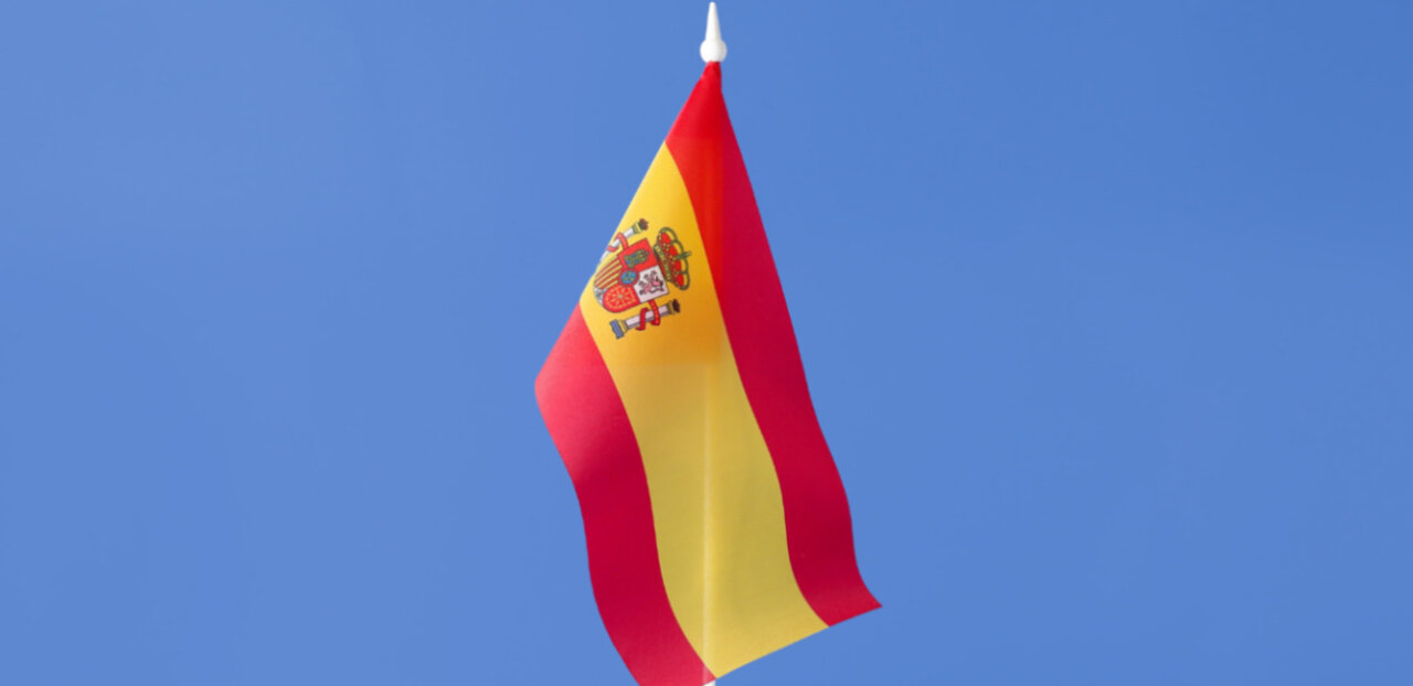 Bandera de España ondeando en un cielo azul claro