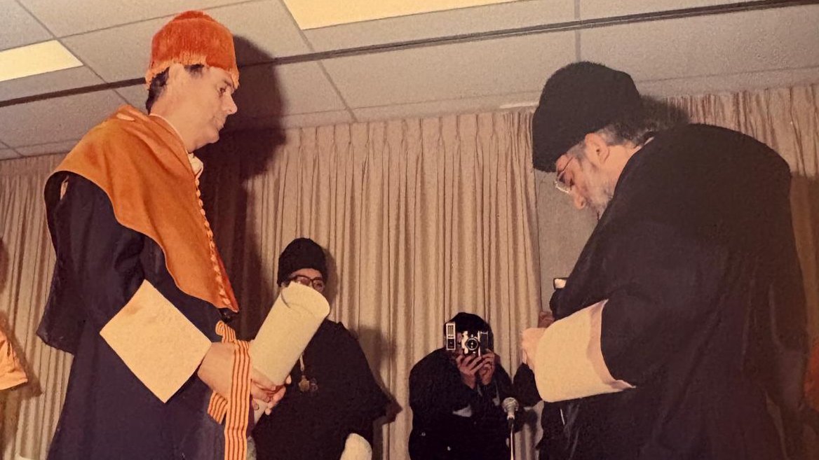 Ceremonia de entrega de título con dos hombres en vestimenta académica.