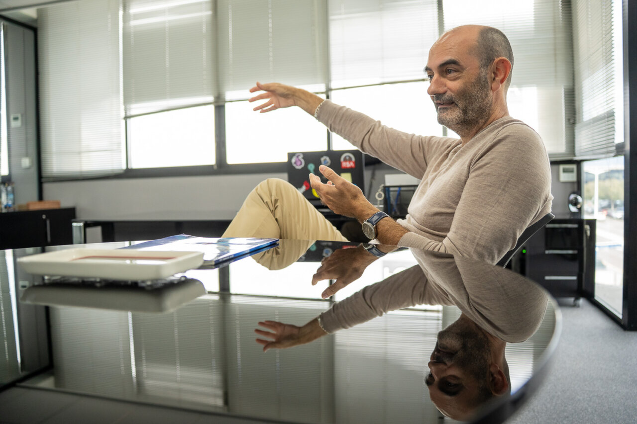 Hombre hablando en una oficina moderna con mesa de cristal.
