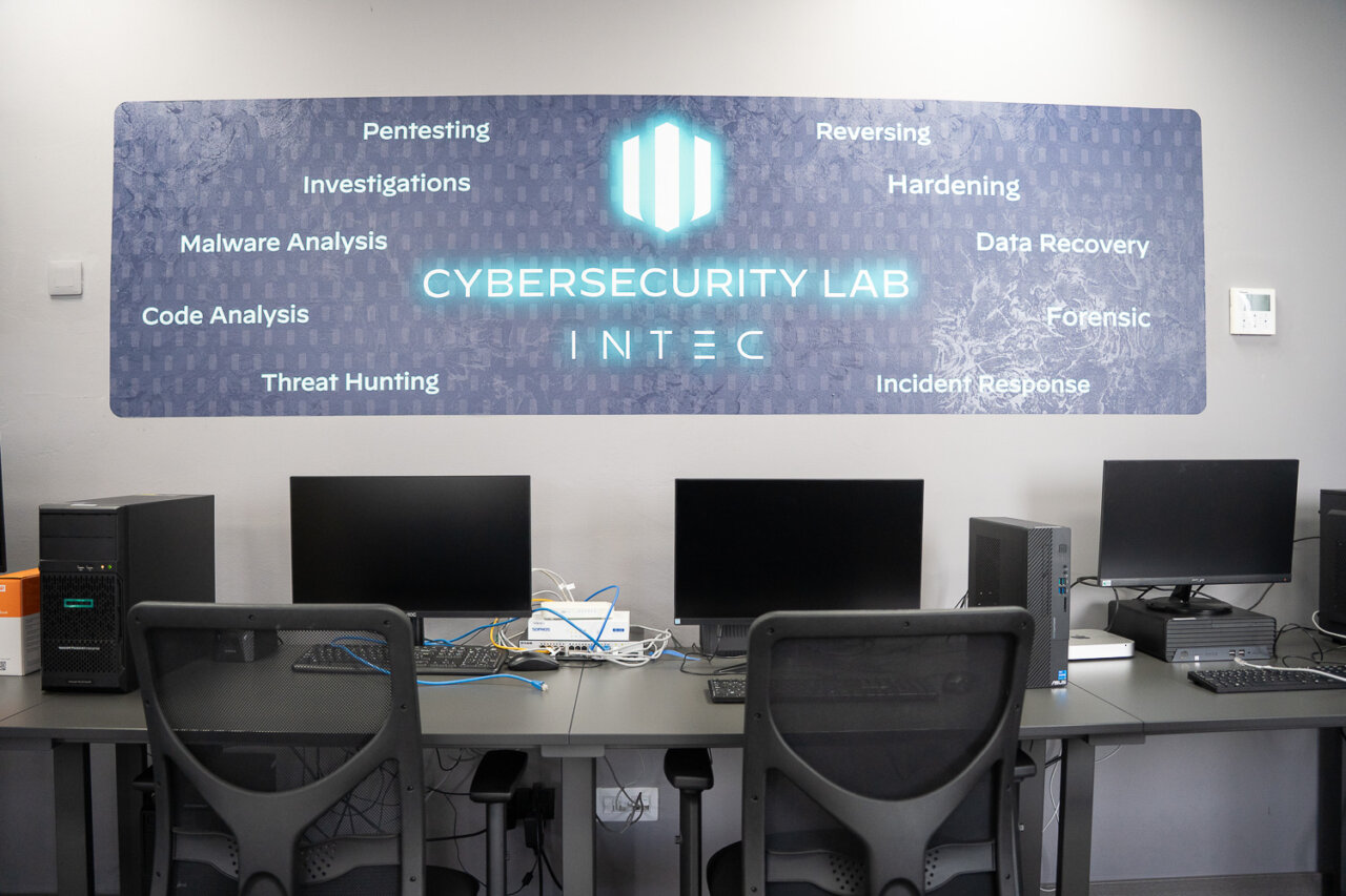 Laboratorio de ciberseguridad en INTEC con computadoras y panel informativo