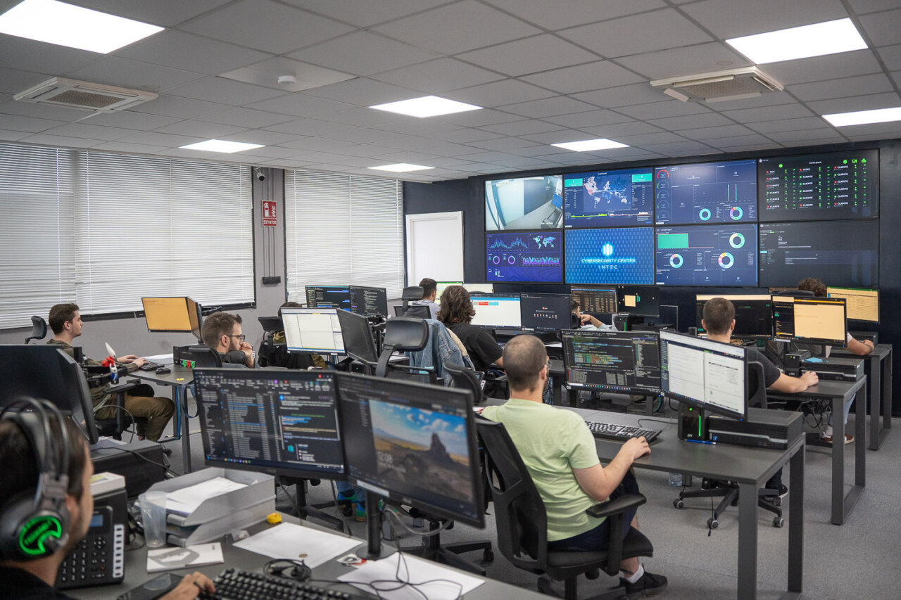 Sala de control de ciberseguridad con varios monitores y profesionales trabajando.