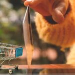 Persona sosteniendo una tarjeta de crédito sobre un carrito de compras pequeño