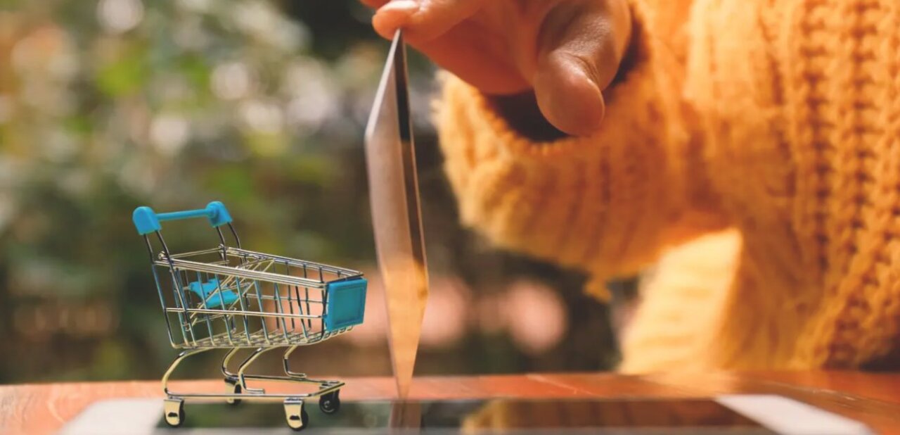 Persona sosteniendo una tarjeta de crédito sobre un carrito de compras pequeño