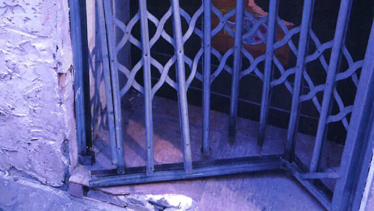 Puerta dañada de un local en Palma tras ocupación ilegal.