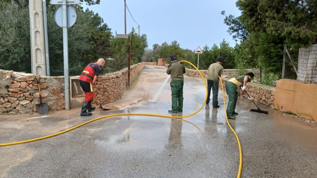Efectivos de emergencias limpiando una calle en Ibiza tras fuertes lluvias