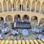 Vista del encuentro de casas regionales en el Castell de Bellver con mesas y participantes.