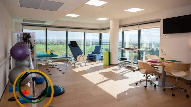 Interior de un espacio de rehabilitación con equipos y ventanas amplias