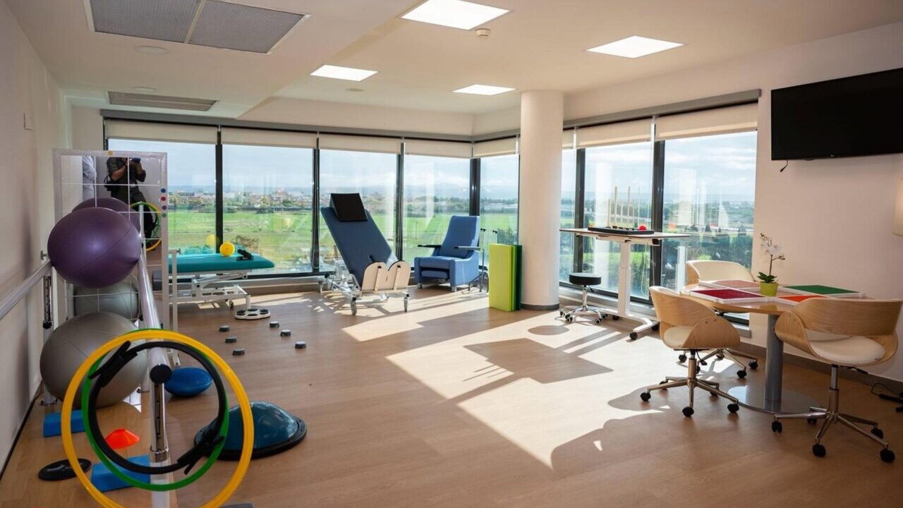 Interior de un espacio de rehabilitaci&oacute;n con equipos y ventanas amplias