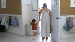 Niño pequeño de la mano de una mujer en una escuela