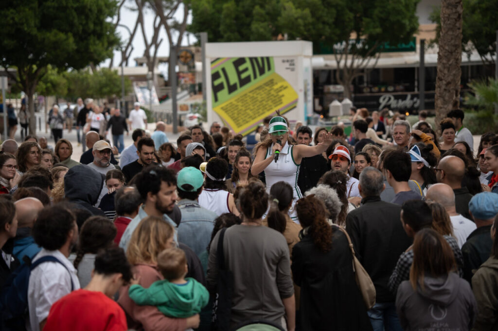 Multitud en el festival FLEM con una presentadora en el centro.