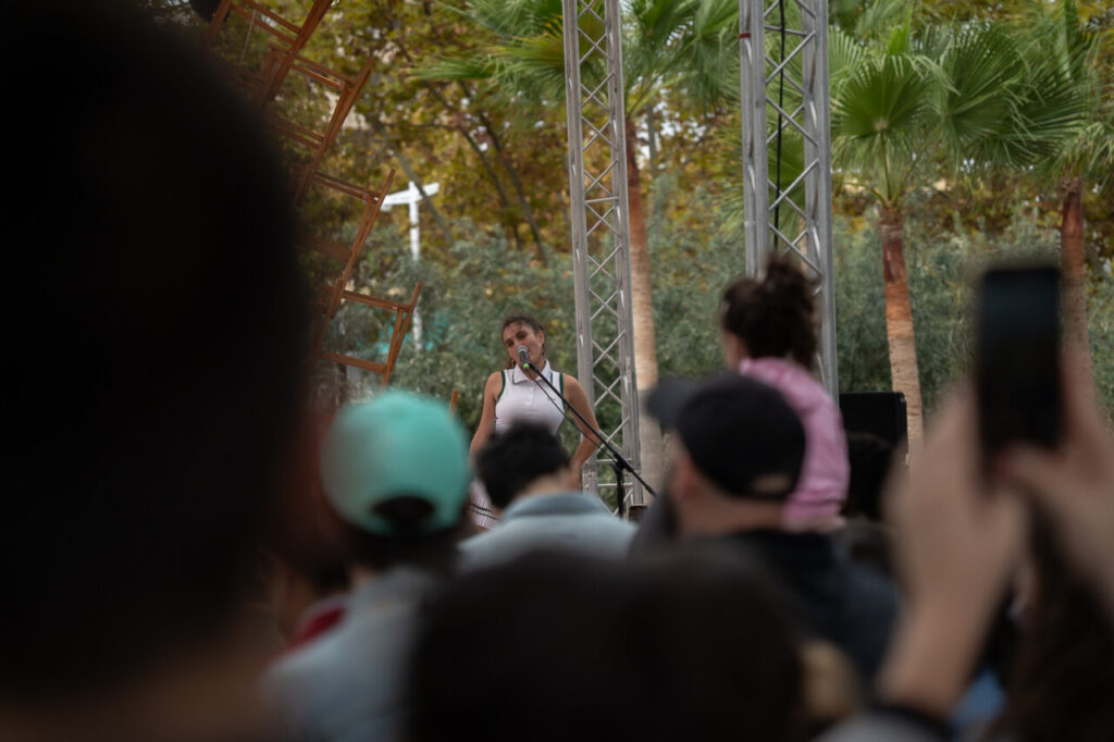 Actuación en el Festival FLEM con público atento y vegetación de fondo.