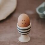 Huevo con cara sonriente en un soporte de cerámica