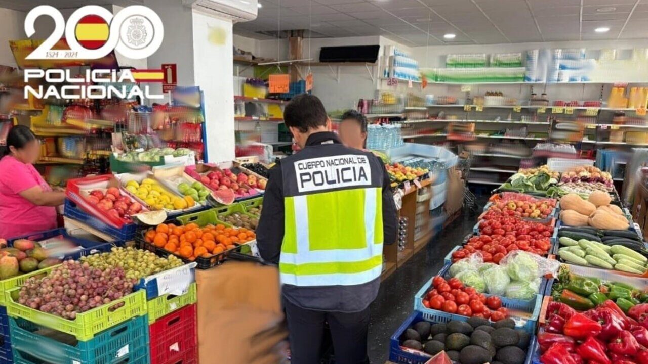 Agente de la Policía Nacional inspeccionando un establecimiento con frutas y verduras.
